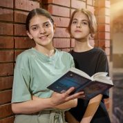 Две девочки читают книжку возле кирпичной стены в театральной студии Irbis
