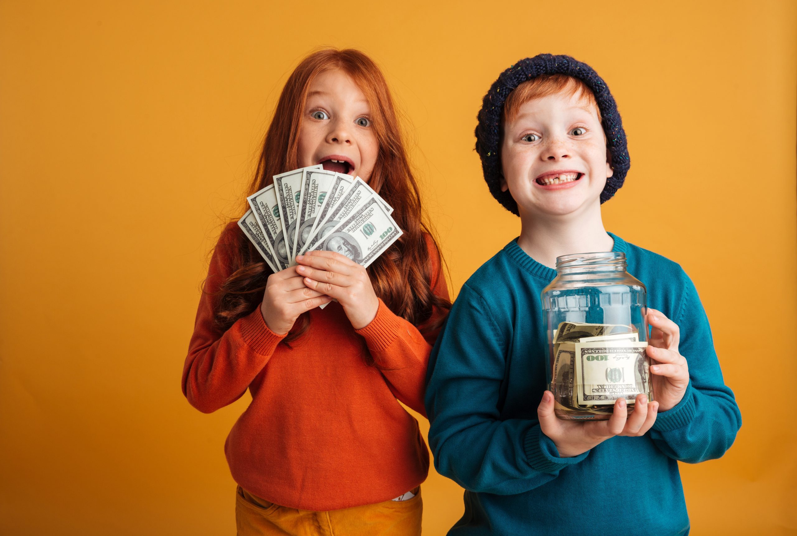 Девочка и мальчик стоят держа в руках бумажные деньги