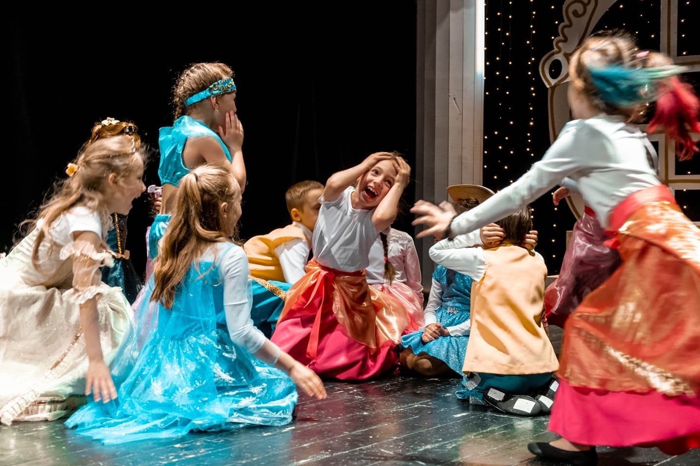 Несколько маленьких девочек дурачатся на сцене театра
