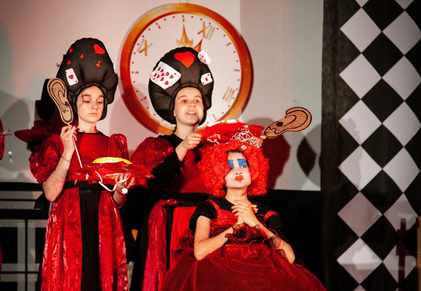 Три маленькие девочки играют сценку из спектакля "Алиса в стране чудес"
